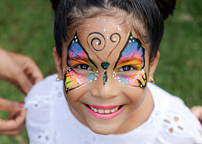 Criança sorrindo com pintura facial colorida